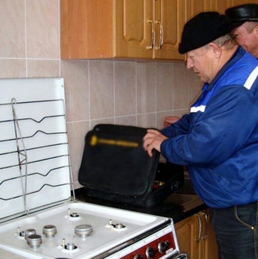 Мастер проверяет утечку газа плиты